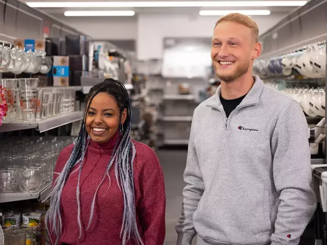Ein Mann und eine Frau stehen in einer modernen Filiale und lächeln.