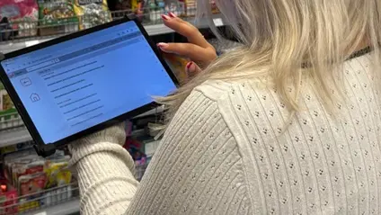 Eine Dame, die mit ihrer Rückseite abgebildet wird, hält ein Tablet in ihrer Hand