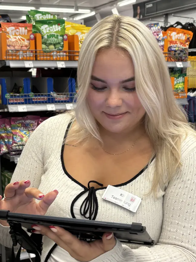 Eine Dame schaut auf ein Tablet, das sie in ihrer Hand hält.
