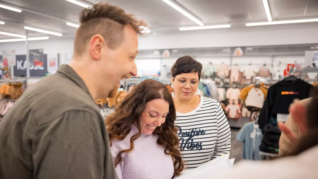 Mehrere Personen stehen in einer Filiale zusammen und lachen.
