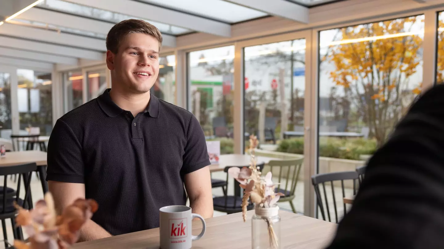 Ein Mann sitzt in einer modernen Räumlichkeit und unterhält sich