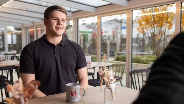 Ein Mann sitzt in einer modernen Räumlichkeit und unterhält sich