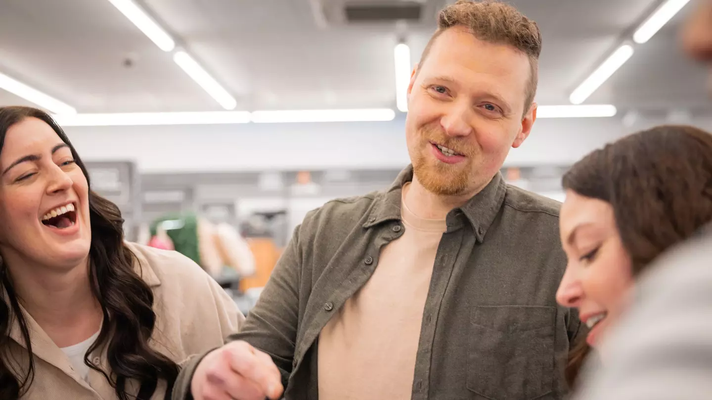 Mitarbeitende lachen gemeinsam bei einem Teamgespräch auf der Verkaufsfläche.