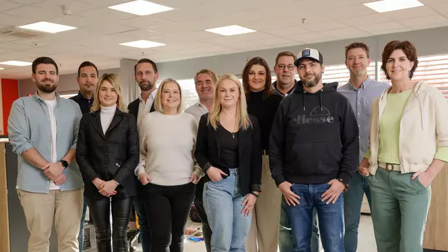 Mitarbeitende posieren im offenen Bürobereich für ein Gruppenfoto