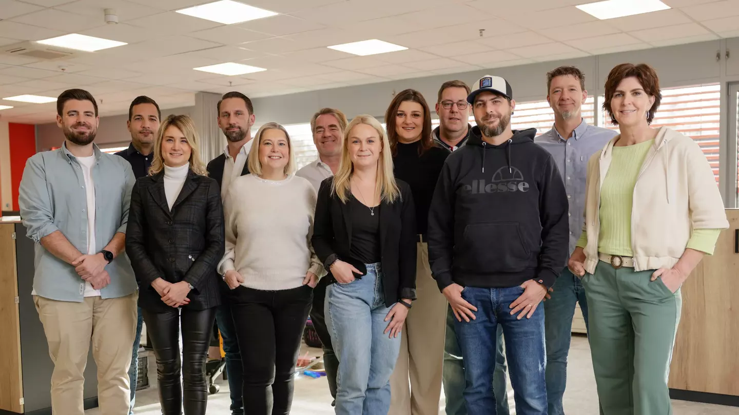 Mitarbeitende posieren im offenen Bürobereich für ein Gruppenfoto.