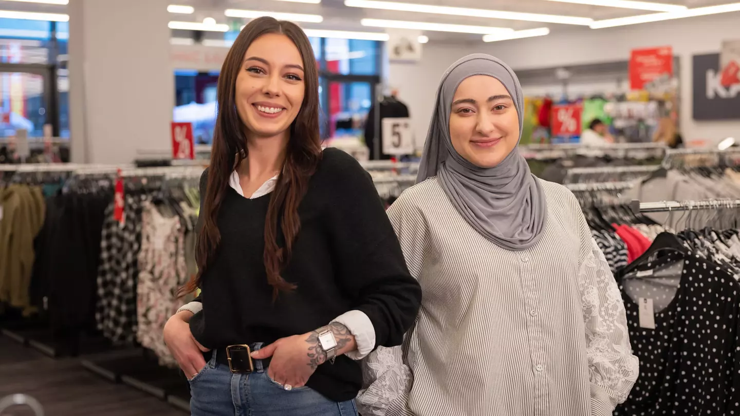 Zwei Mitarbeiterinnen stehen lächelnd in einer modernen Filiale