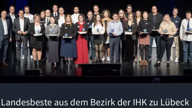 Gruppe Auszubildender mit Auszeichnungen steht auf einer Bühne bei IHK-Ehrung der Landesbesten im Bezirk Lübeck.