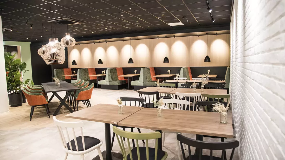 Innenansicht einer modern eingerichteten Kantine mit Tischen, Stühlen und Sitznischen.
