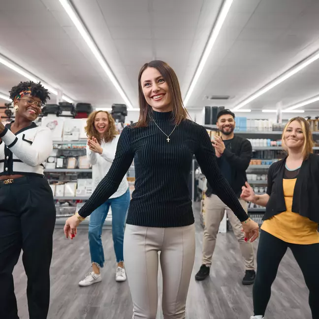 Kolleginnen tanzen und lachen in der Filiale.